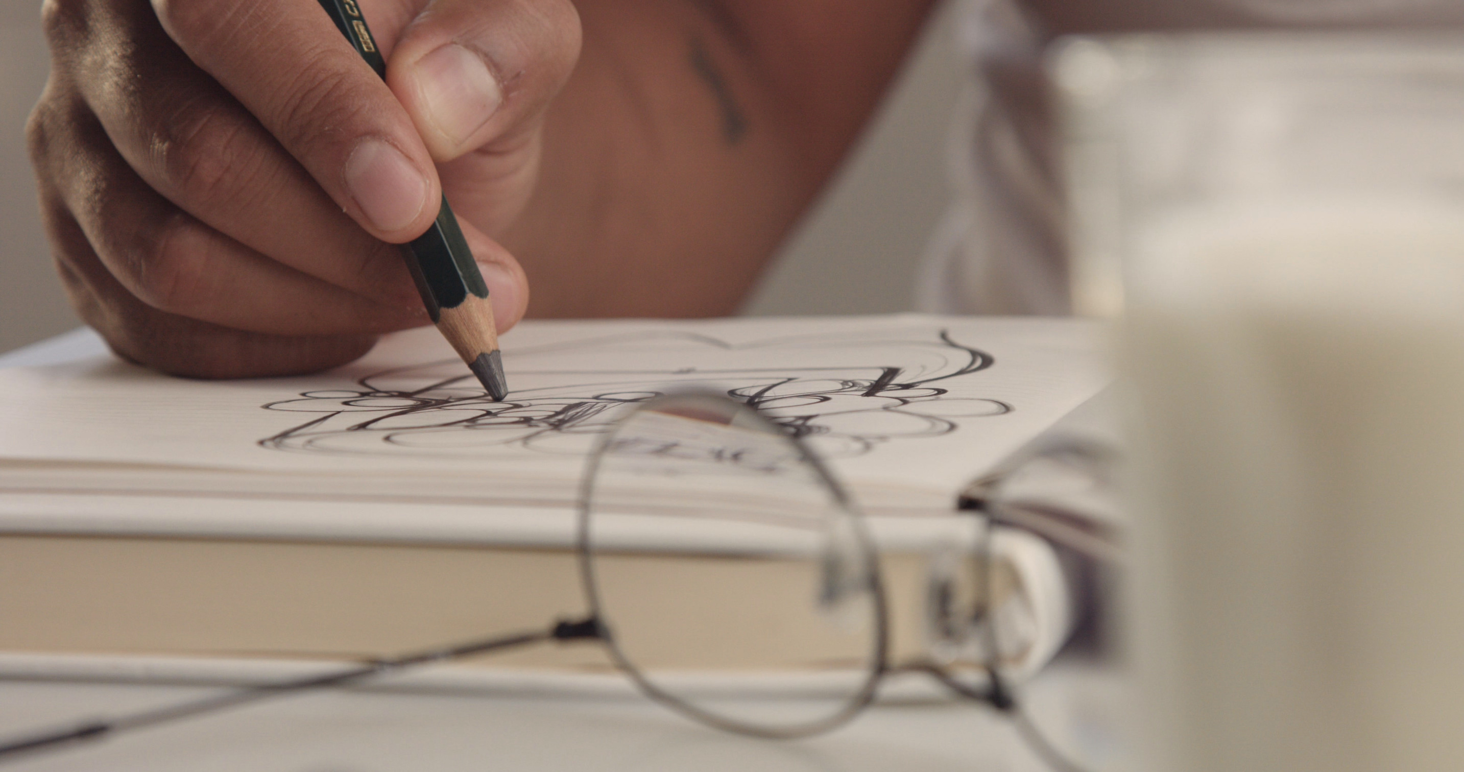 A man reviews a printed manuscript with neat red-pen corrections at a pale oak table, beside a notebook and a cup of tea